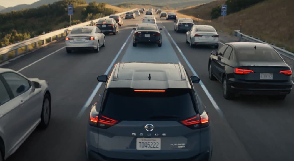A black 2021 Nissan Rogue is shown from a rear angle while driving.