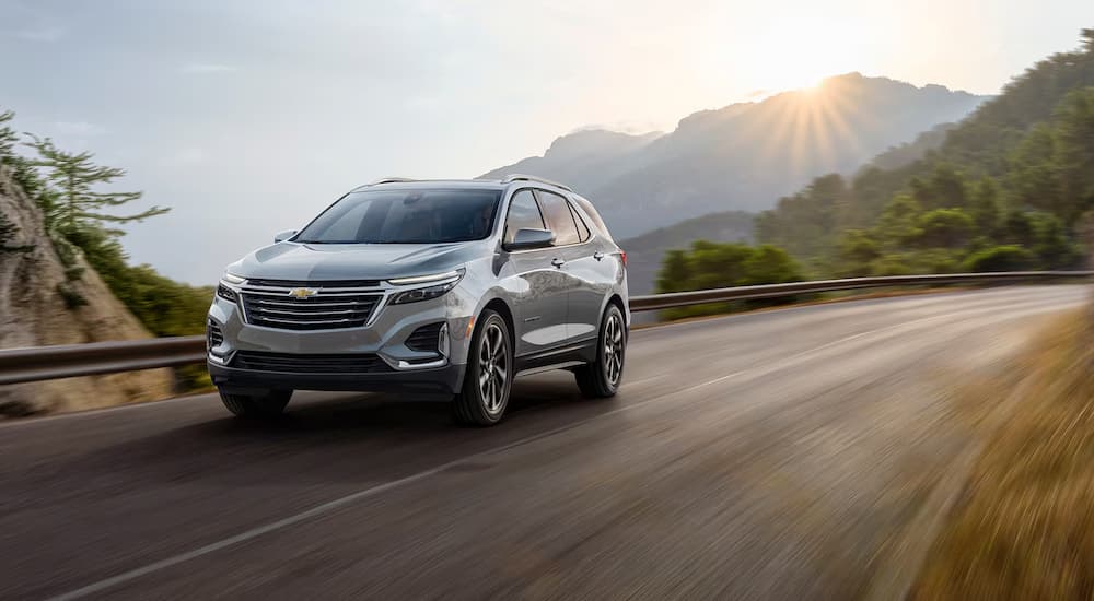 A silver 2024 Chevy Equinox driving on an open mountain road.