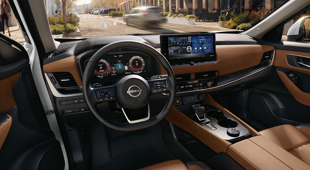 The brown leather interior and multiple digital displays in a 2024 Nissan Rogue Platinum for sale.