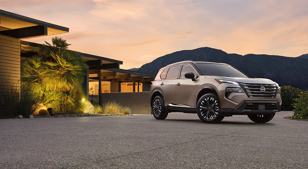A silver 2024 Nissan Rogue Platinum parked outside a home at dusk.