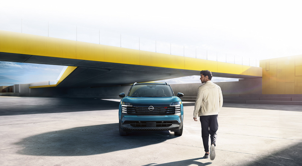 A man walking towards a blue 2025 Nissan Kicks.