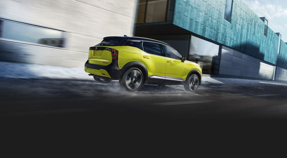 Rear view of a lime green 2025 Nissan Kicks driving on a wet street.