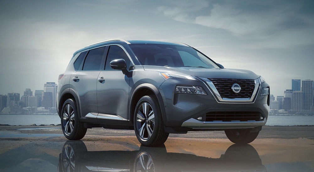 A silver 2024 Nissan Rogue parked in front of a cityscape.