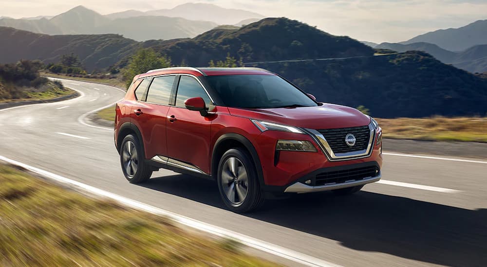 A red 2024 Nissan Rogue driving to a Nissan dealer near LaFollette.