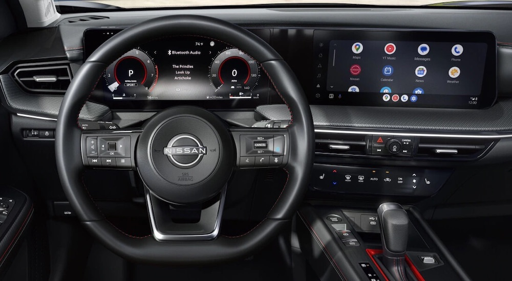 The black interior of a 2025 Nissan Kicks is shown from the driver's seat.