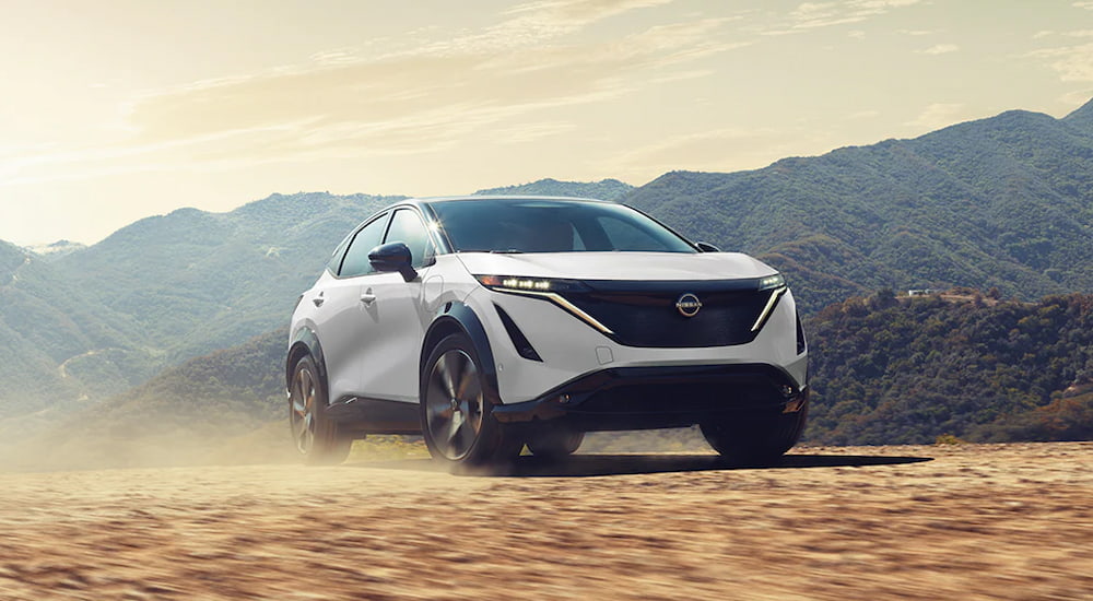 A white 2025 Nissan ARIYA Platinum driving through a desert.
