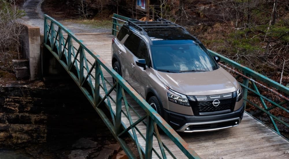 A tan 2025 Nissan Pathfinder for sale crossing a bridge.