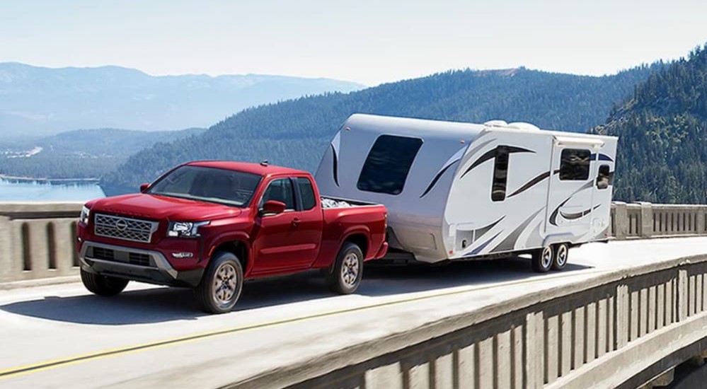 A red 2025 Nissan Frontier towing a trailer to a Nissan dealer in Knoxville.