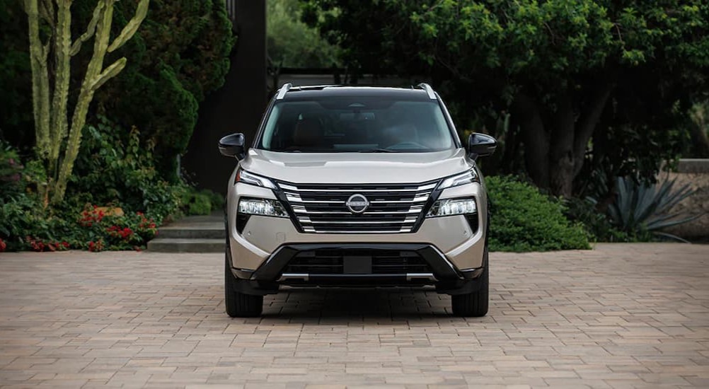 A tan 2025 Nissan Rogue SV is parked near a Nissan dealer in Knoxville.