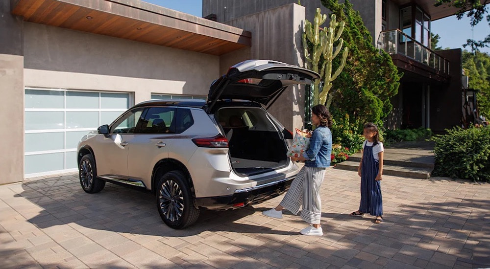 Woman opening the hatch of a tan 2025 Nissan Rogue SV.
