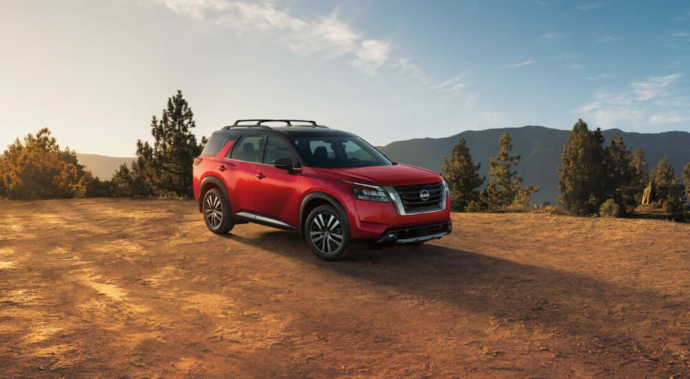 A red 2025 Nissan Pathfinder parked off-road on dirt