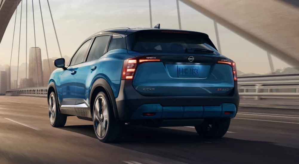 A blue 2026 Nissan Kicks for sale in Knoxville driving on a bridge.