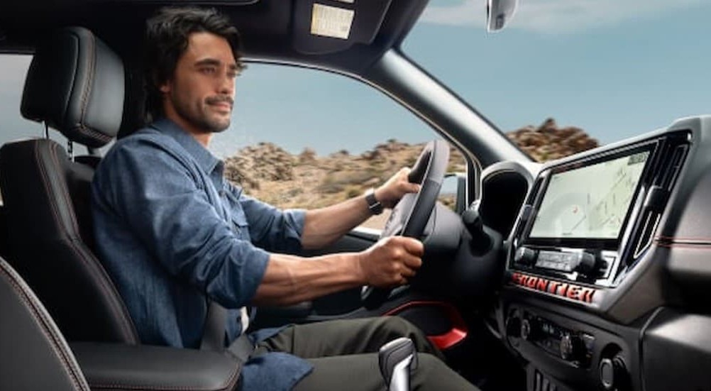 A person driving in a 2026 Nissan Frontier.