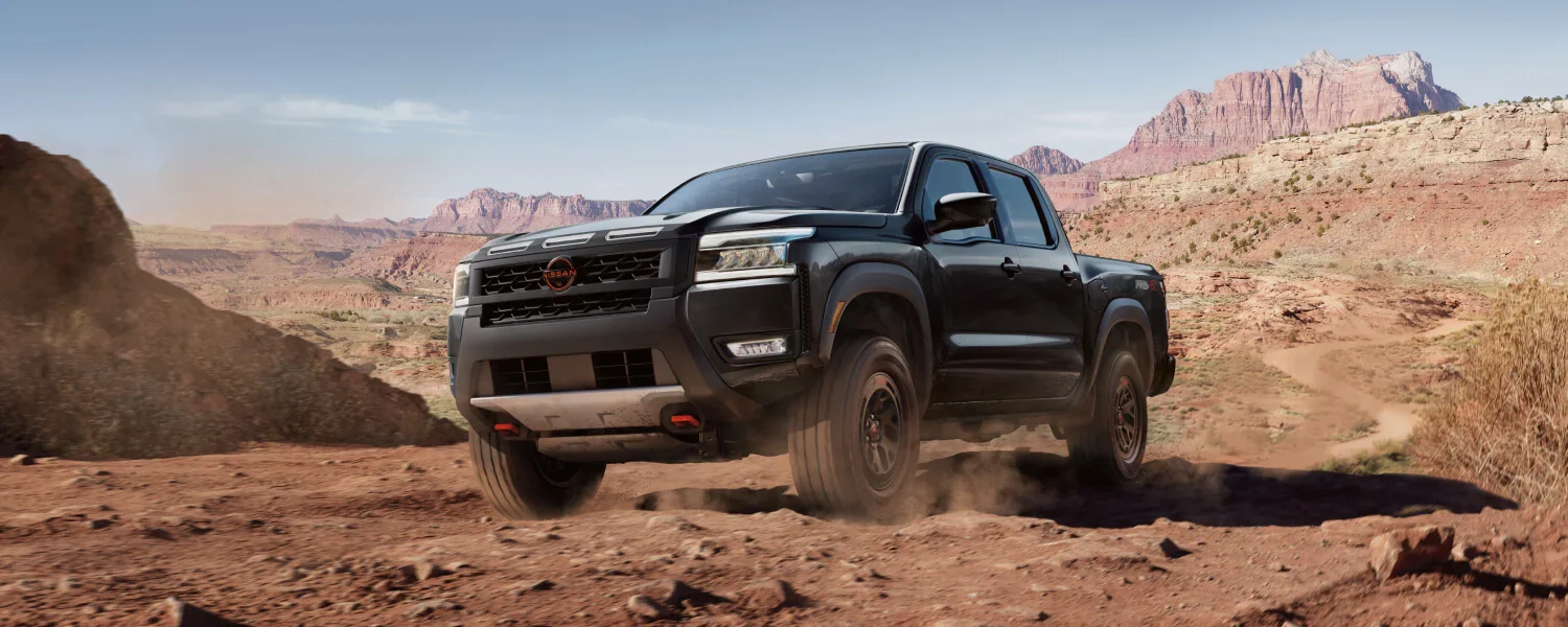 Black 2026 Nissan Frontier driving off-road.