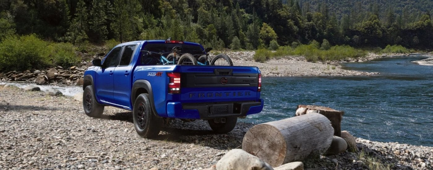 Blue 2025 Nissan Frontier PRO 4X parked by a lake