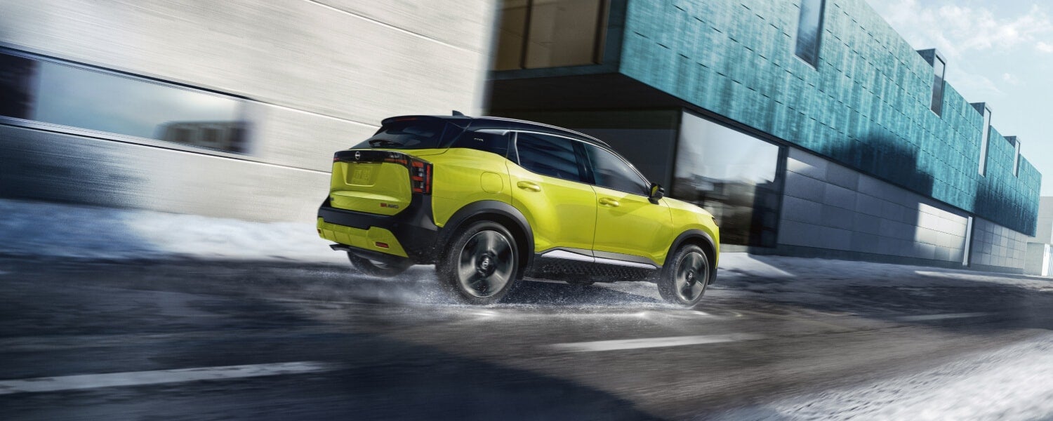 Rear of a yellow 2026 Nissan Kicks SR driving in a city