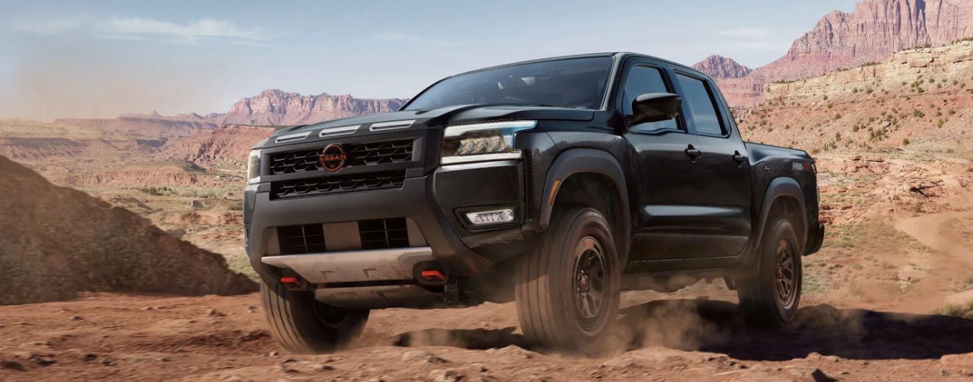 Black 2026 Nissan Frontier driving off-road.