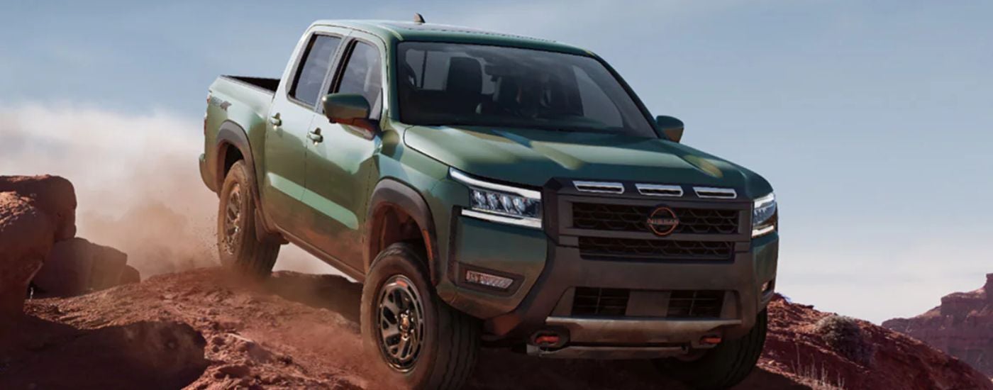 Green 2026 Nissan Frontier driving off-road.