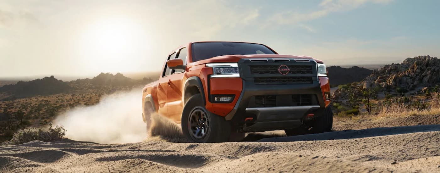 Red 2026 Nissan Frontier driving off-road.