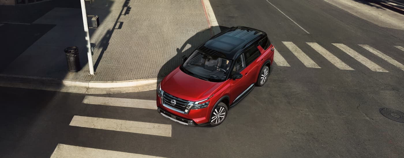 High view of a red 2026 Nissan Pathfinder driving around a bend.
