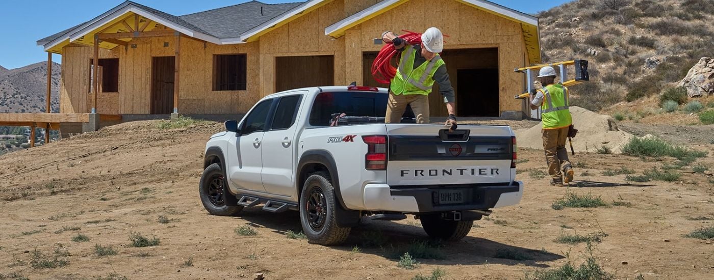 Rear view of a white 2026 Nissan Frontier parked on a construction site.