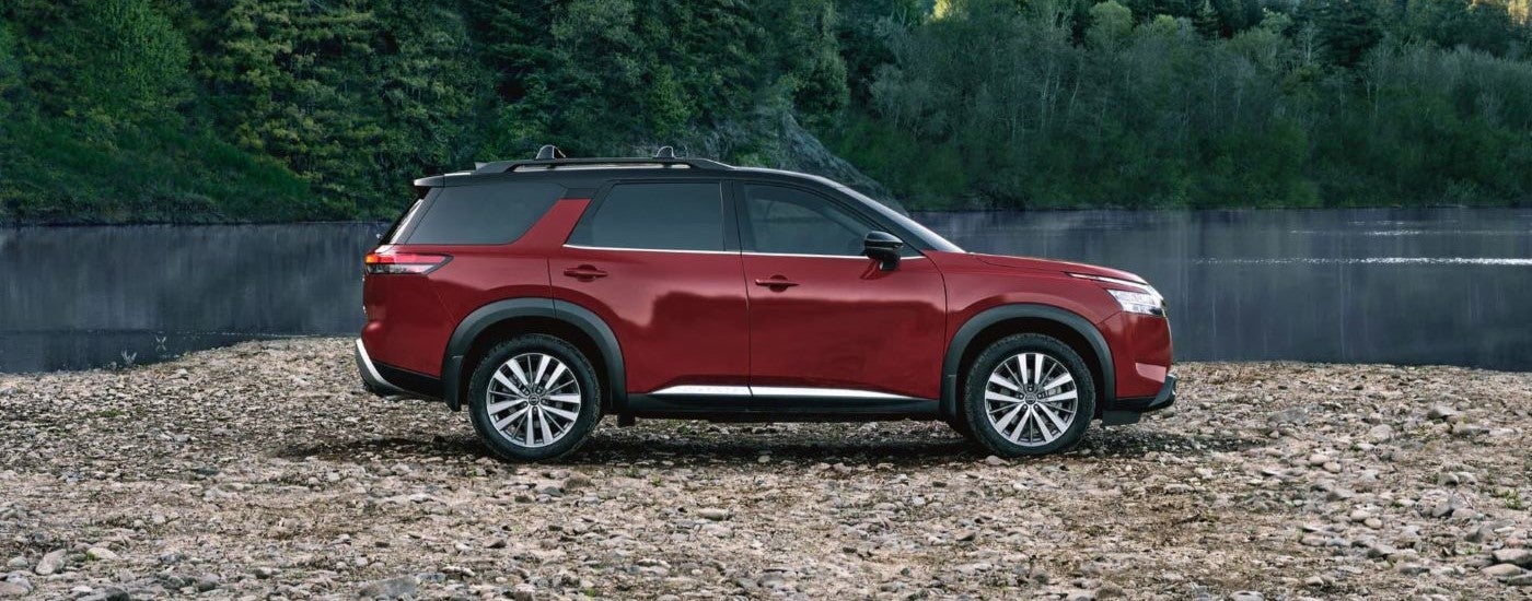 A red 2023 Nissan Pathfinder parked by a lake.