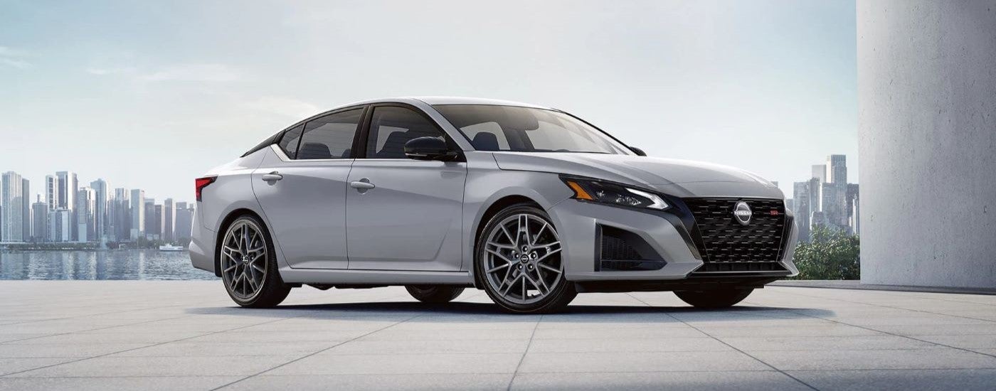 Right angled view of a white 2023 Nissan Altima SR parked by a Nissan dealer near Clinton.