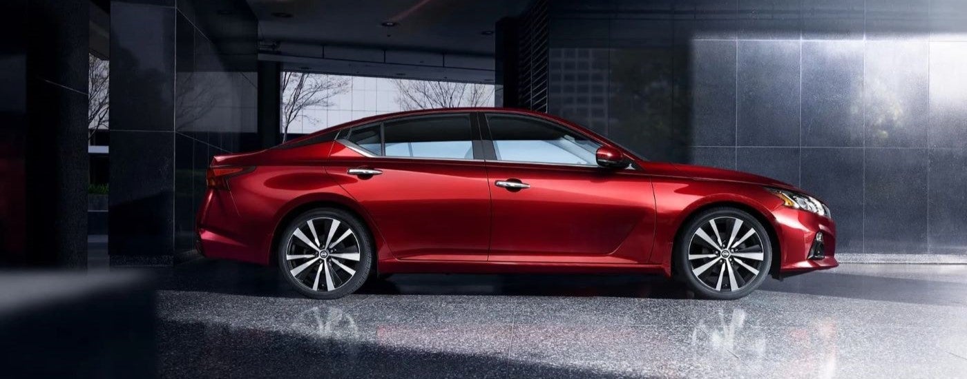 Side view of a red 2019 Nissan Altima parked in a showroom.