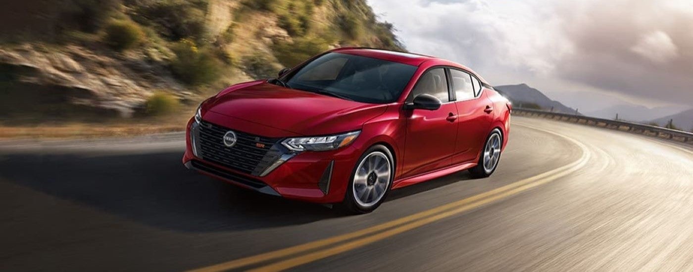 A red 2024 Nissan Sentra SR driving around a bend.
