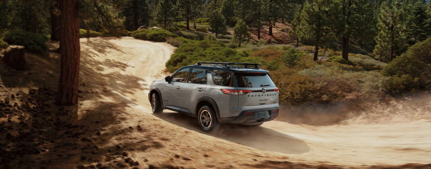 Rear view of a grey 2025 Nissan Pathfinder driving through a forest.