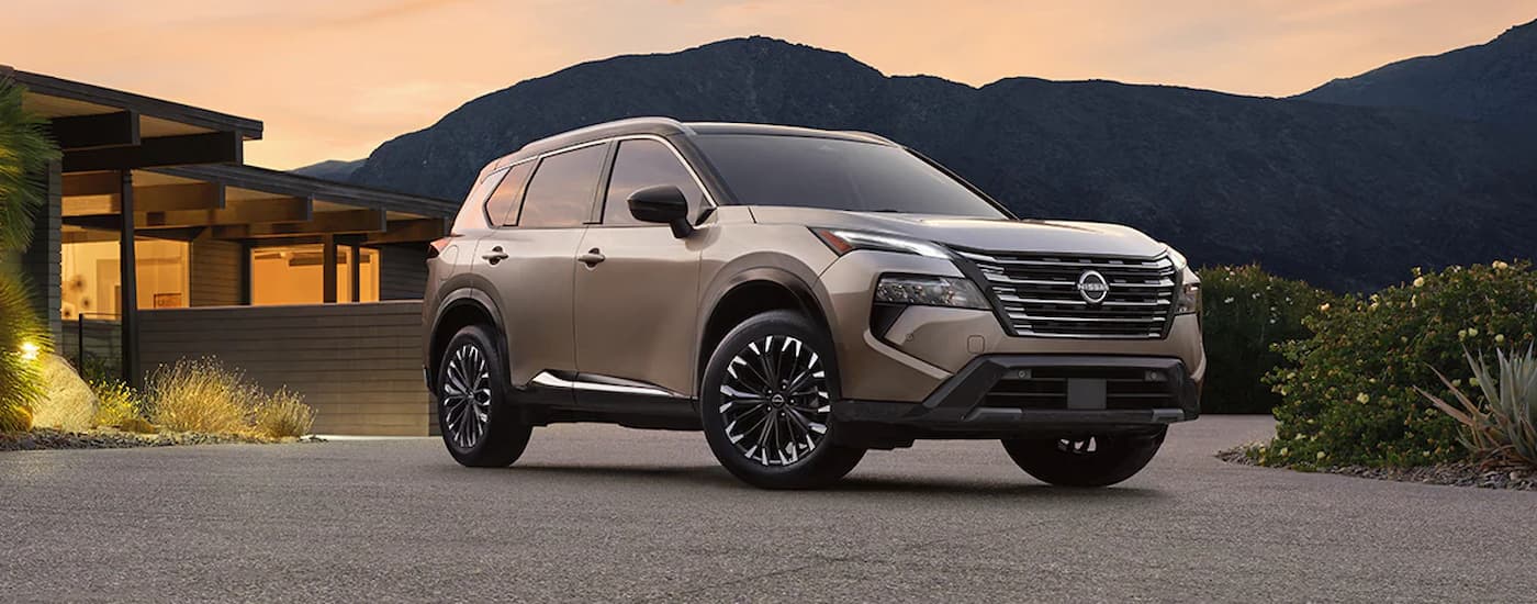 A tan 2024 Nissan Rogue for sale is parked with a mountain view.