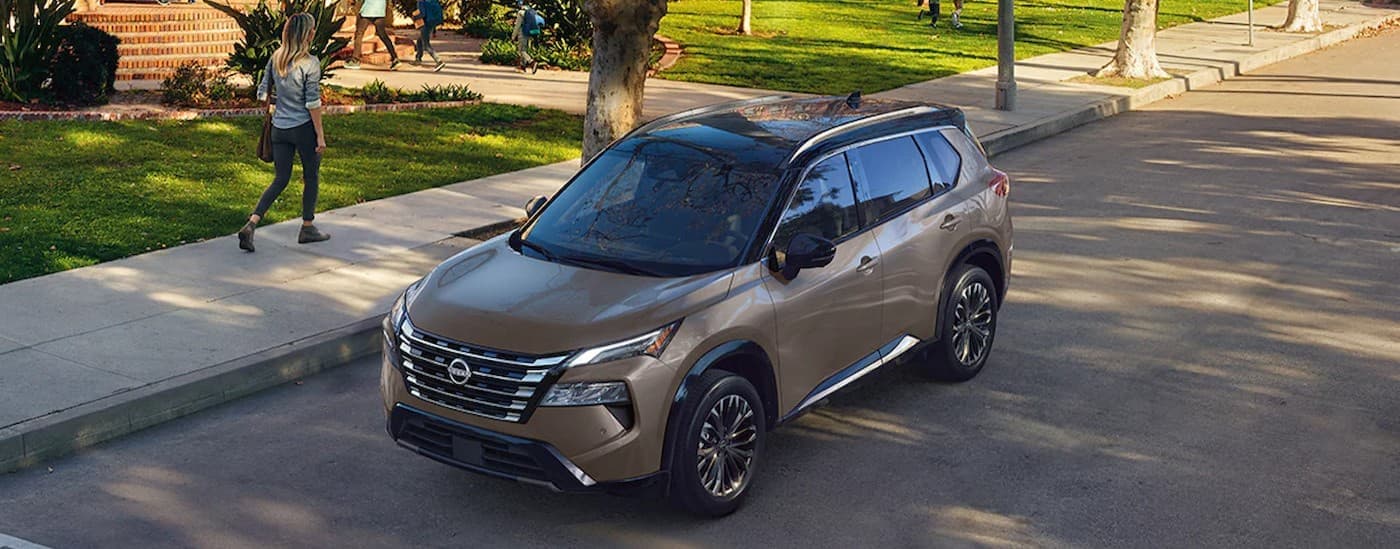 A tan 2024 Nissan Rogue parked near a school.