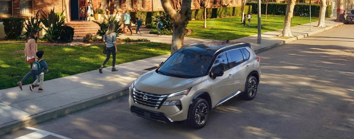 A grey Nissan Rogue for sale in Knoxville parked in front of a school.