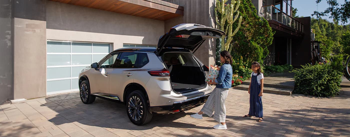 Woman using the rear tailgate on a white 2025 Nissan Rogue
